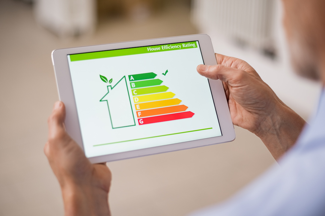 Person betrachtet auf einem Tablet die Energieeffizienz-Skala eines Hauses von A bis G